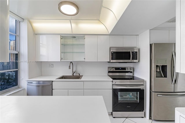 kitchen with appliances with stainless steel finishes, white cabinets, light countertops, and a sink