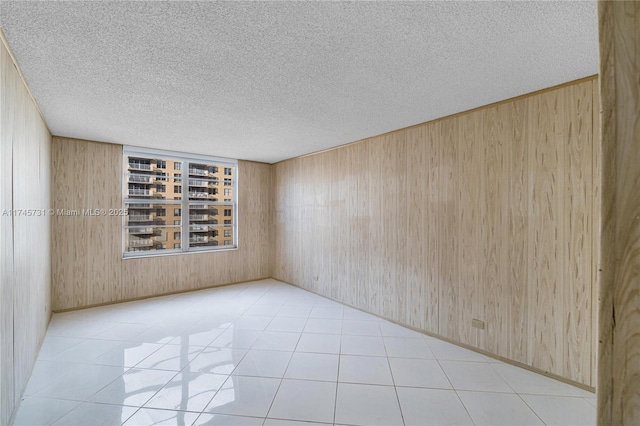 tiled empty room with a textured ceiling and wood walls