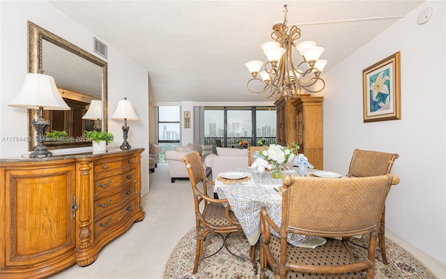 dining space featuring a textured ceiling, light carpet, visible vents, and an inviting chandelier