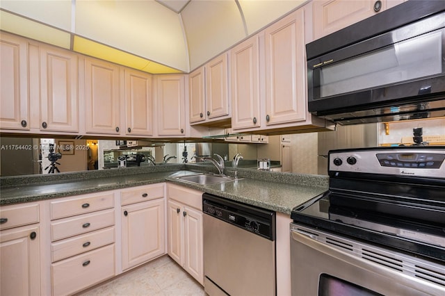 kitchen featuring light tile patterned floors, stainless steel appliances, dark countertops, and a sink