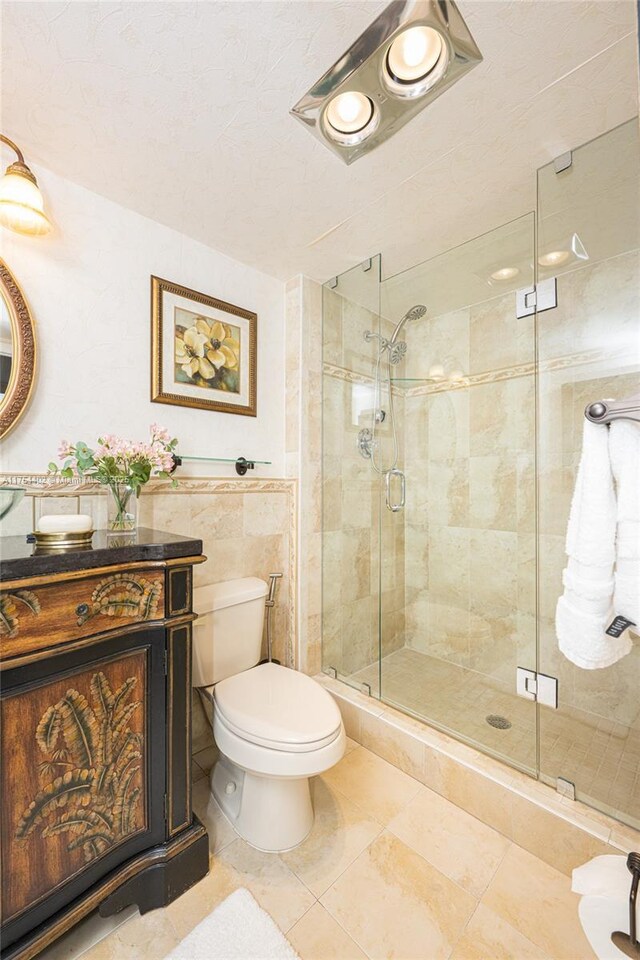 bathroom with a stall shower, tile walls, vanity, and toilet