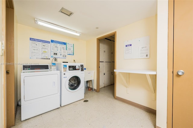 community laundry room with washing machine and dryer, baseboards, and light floors