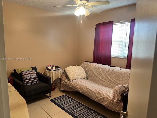 living room with light tile patterned floors, ceiling fan, and a textured ceiling