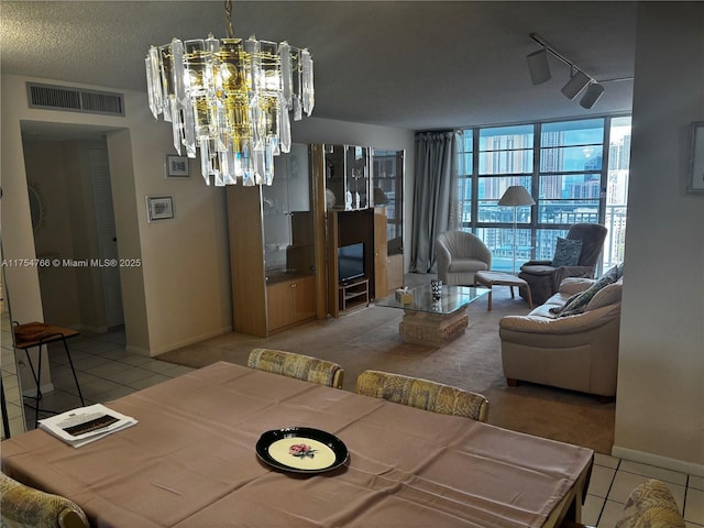 tiled dining space featuring a notable chandelier, visible vents, a textured ceiling, track lighting, and a wall of windows