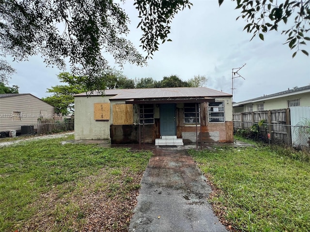 view of front facade featuring central AC, fence, and a front lawn