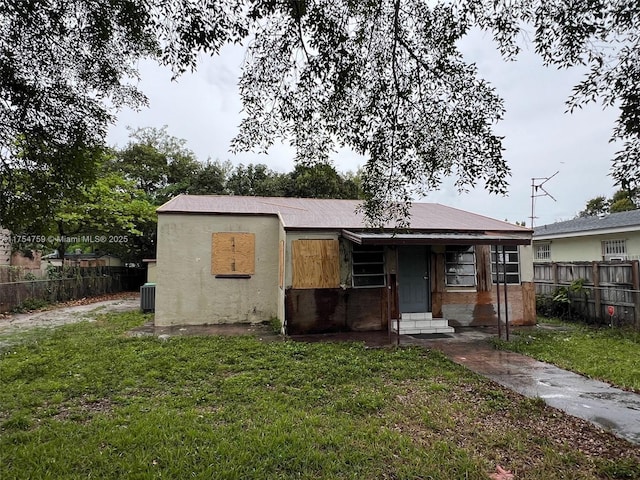 view of front facade with entry steps, central air condition unit, fence, stucco siding, and a front lawn