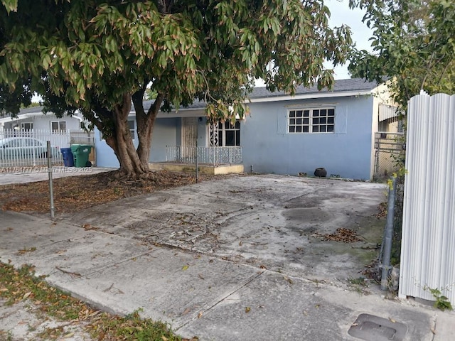 single story home with covered porch, fence, and stucco siding