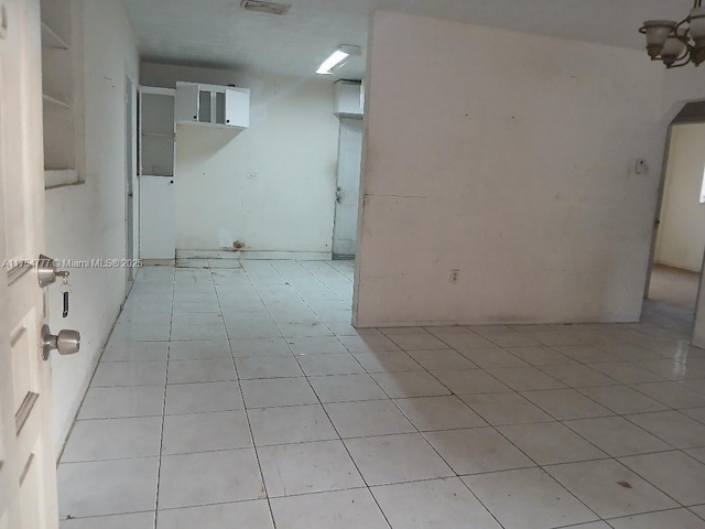 unfurnished room featuring arched walkways and light tile patterned flooring