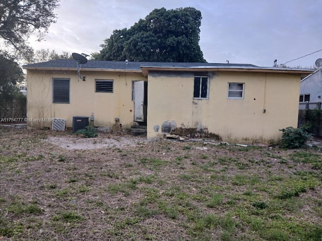 rear view of property featuring entry steps, central AC, and stucco siding