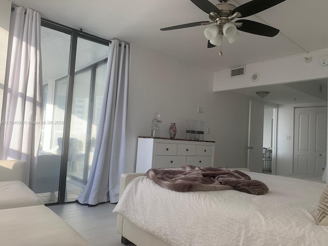 bedroom with access to exterior, ceiling fan, expansive windows, and visible vents