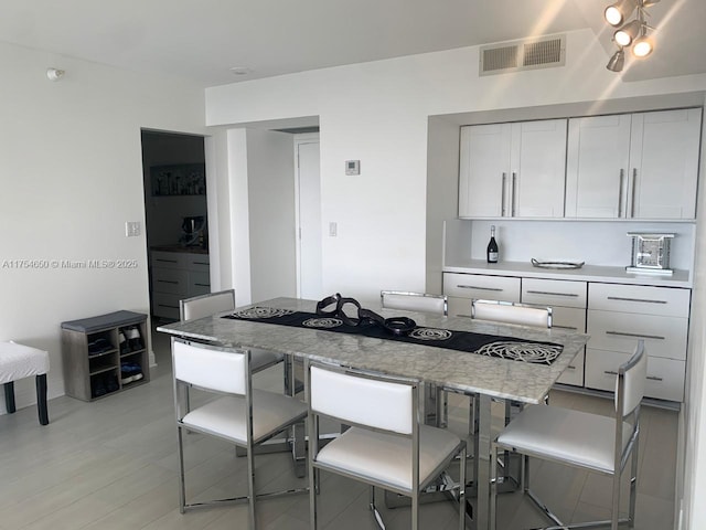 kitchen with a breakfast bar, visible vents, and white cabinets