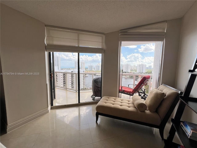 living area with tile patterned floors, baseboards, a view of city, and a textured ceiling