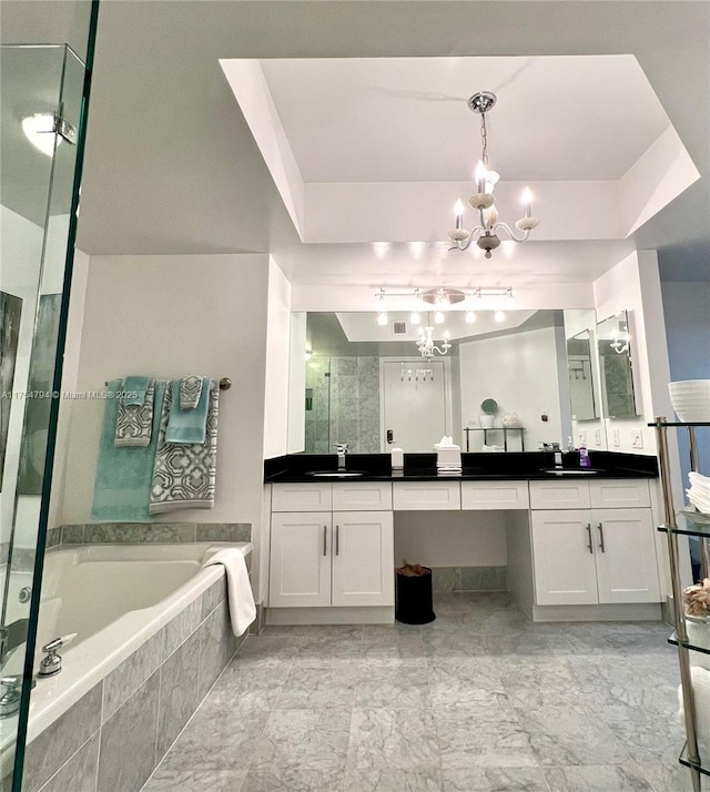 bathroom with an inviting chandelier, a shower stall, vanity, and a garden tub