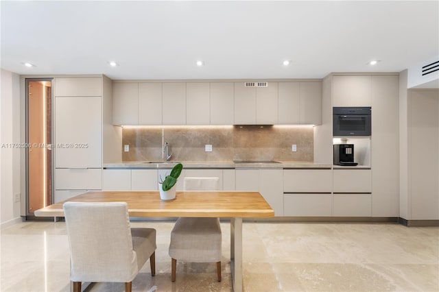 kitchen with light countertops, black electric stovetop, modern cabinets, and decorative backsplash