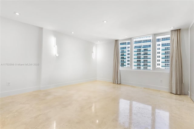 empty room featuring finished concrete flooring, recessed lighting, and baseboards