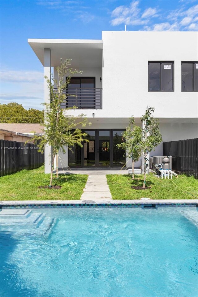 3430 SW 2nd St, Miami, FL 33135 - rear view of house with a fenced in pool, fence, a balcony, and stucco siding