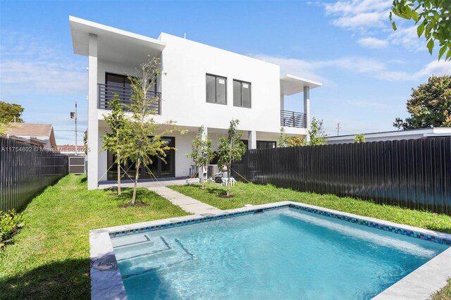 3430 SW 2nd St, Miami, FL 33135 - rear view of house with a fenced in pool, a yard, stucco siding, a balcony, and a fenced backyard
