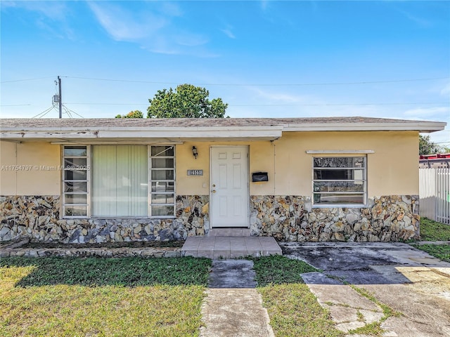 view of front of property with stone siding, fence, and stucco siding