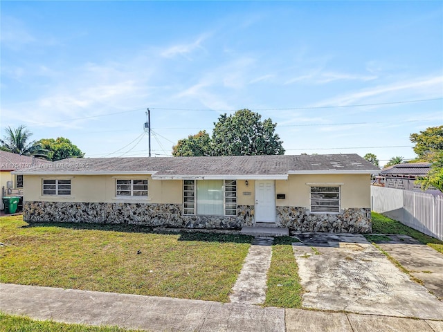 single story home with stone siding, a front yard, fence, and stucco siding