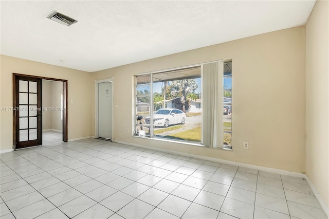 unfurnished room with french doors, visible vents, baseboards, and light tile patterned floors