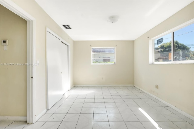 unfurnished room with baseboards and visible vents