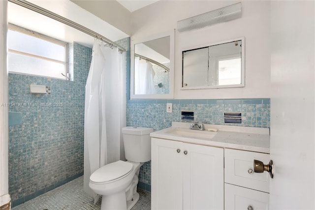 full bathroom with toilet, a tile shower, tile walls, and vanity