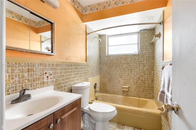 full bathroom featuring toilet, a wainscoted wall, vanity, washtub / shower combination, and tile walls