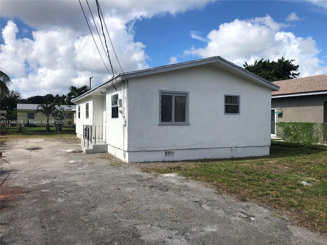 view of home's exterior with crawl space and stucco siding