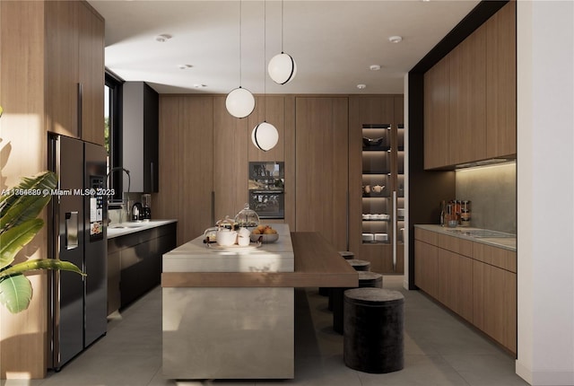 kitchen with pendant lighting, stainless steel refrigerator with ice dispenser, light countertops, modern cabinets, and black electric cooktop