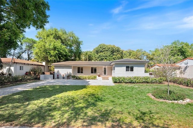 ranch-style home with driveway, a front lawn, and stucco siding