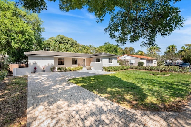 single story home with a front lawn, decorative driveway, and fence