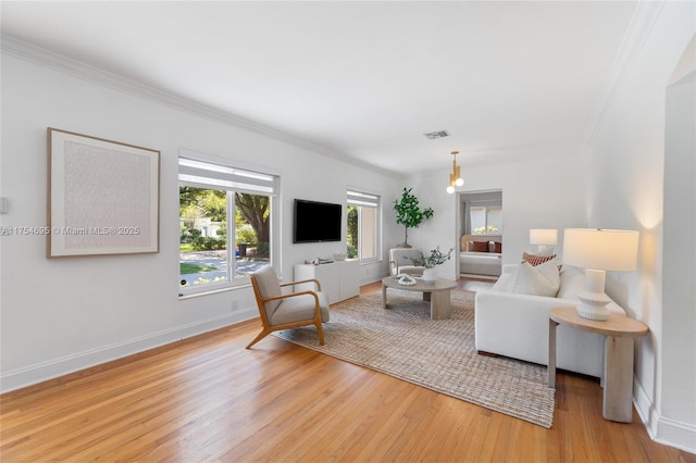 living area with light wood finished floors, baseboards, and ornamental molding