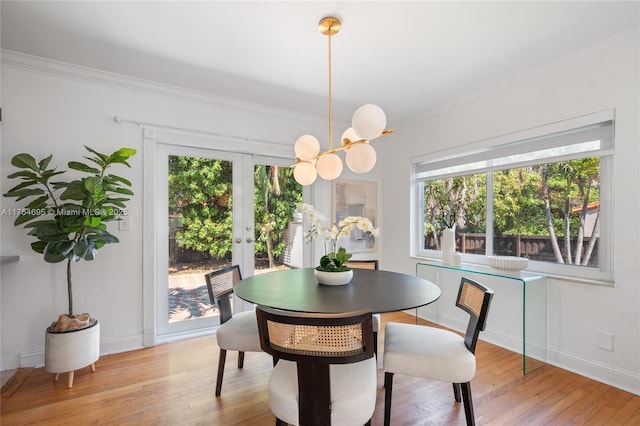 dining room with an inviting chandelier, crown molding, baseboards, and wood finished floors