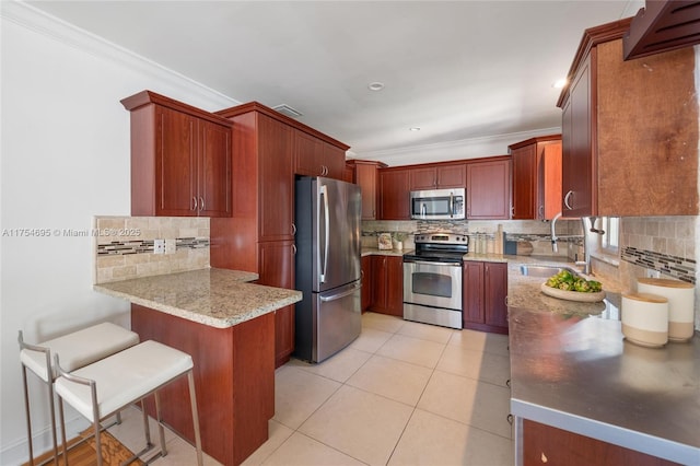 kitchen with light tile patterned floors, a peninsula, stainless steel appliances, crown molding, and a sink