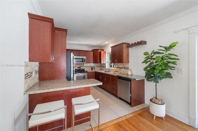 kitchen with crown molding, decorative backsplash, appliances with stainless steel finishes, a sink, and a peninsula