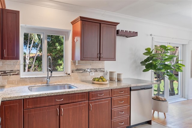 kitchen with stainless steel dishwasher, crown molding, backsplash, and a sink