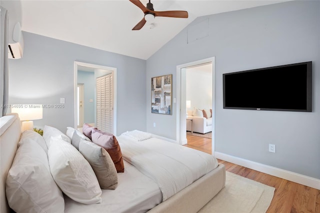 bedroom with a wall unit AC, lofted ceiling, ceiling fan, wood finished floors, and baseboards