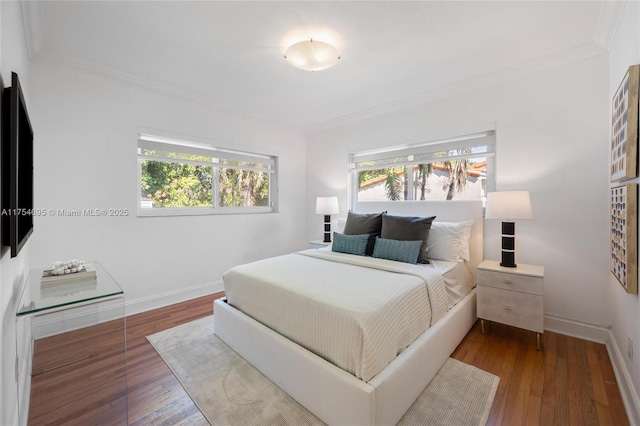 bedroom with ornamental molding, wood-type flooring, and baseboards