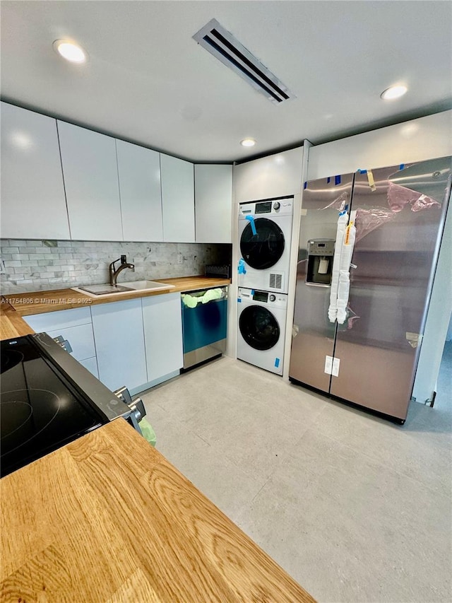 555 Crandon Blvd Unit 32, Key Biscayne, FL 33149 - kitchen with dishwasher, estacked washer and dryer, a sink, backsplash, and white cabinets