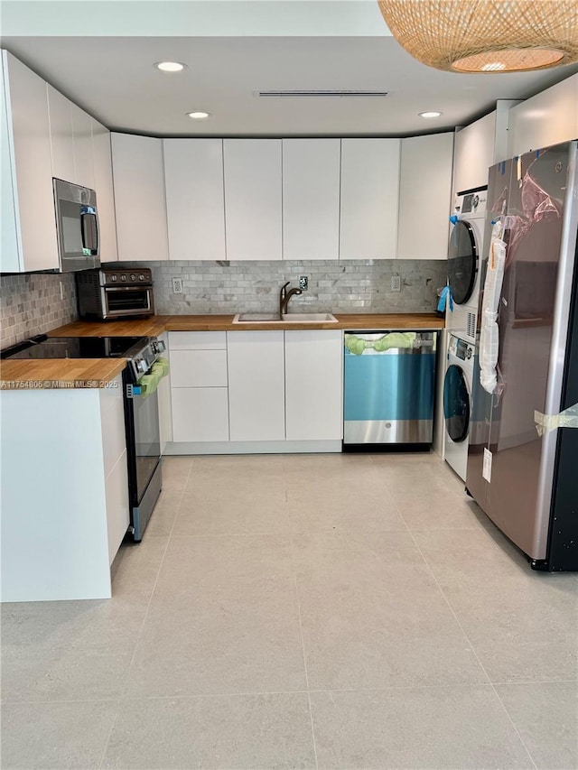 555 Crandon Blvd Unit 32, Key Biscayne, FL 33149 - kitchen featuring stainless steel appliances, a sink, stacked washer and clothes dryer, backsplash, and white cabinets