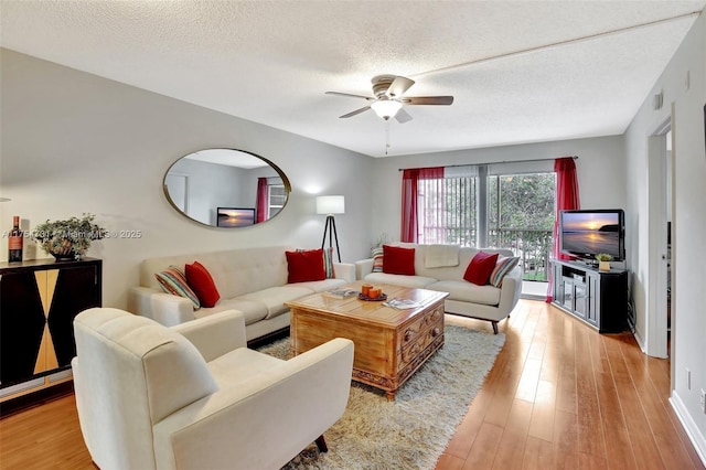 living room featuring ceiling fan, a textured ceiling, and wood finished floors