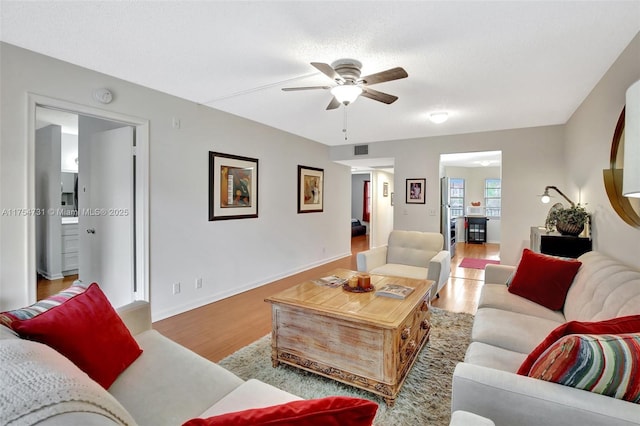 living area with visible vents, baseboards, ceiling fan, a textured ceiling, and light wood-type flooring