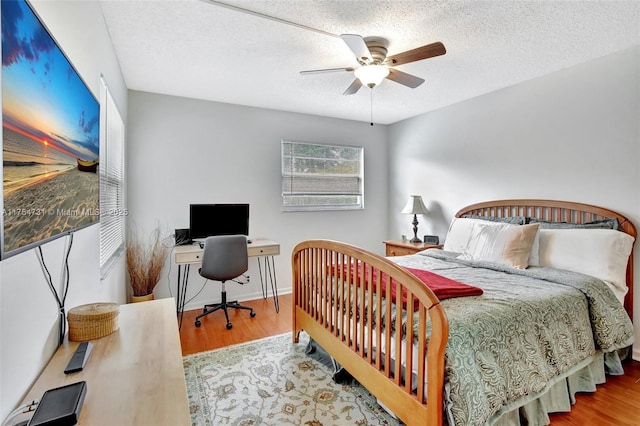 bedroom with a textured ceiling, wood finished floors, a ceiling fan, and baseboards