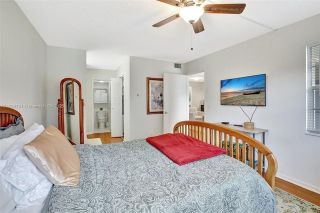 bedroom with visible vents, connected bathroom, ceiling fan, wood finished floors, and a textured ceiling