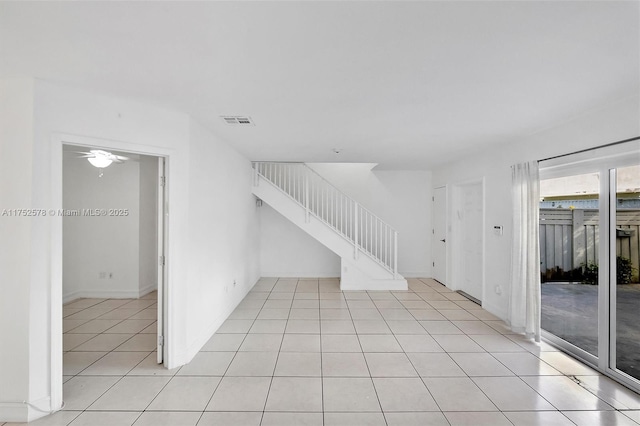 empty room featuring stairs, light tile patterned floors, and visible vents