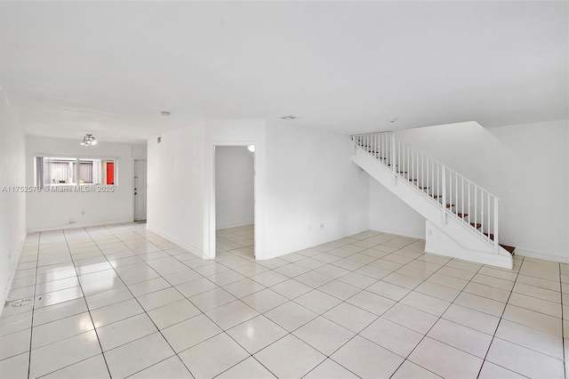 unfurnished room featuring stairway, light tile patterned flooring, visible vents, and baseboards