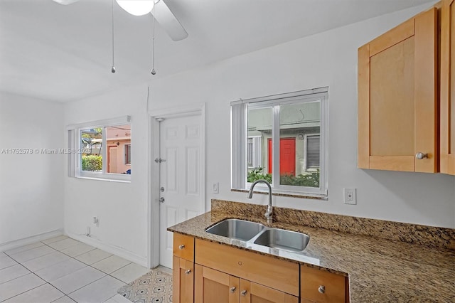 kitchen with baseboards, stone countertops, a ceiling fan, and a sink