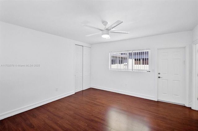 empty room with dark wood-style floors, ceiling fan, and baseboards