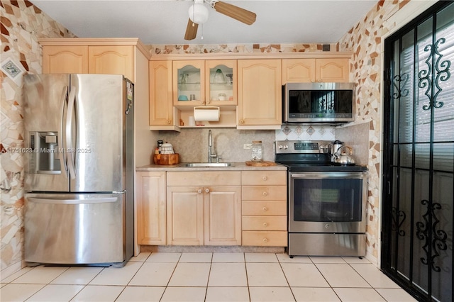 kitchen featuring light tile patterned floors, appliances with stainless steel finishes, light countertops, light brown cabinetry, and a sink