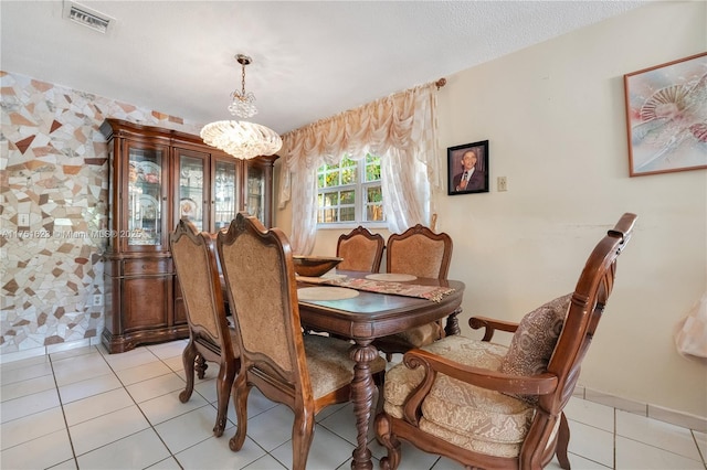 dining room with a chandelier, a textured ceiling, light tile patterned flooring, and visible vents